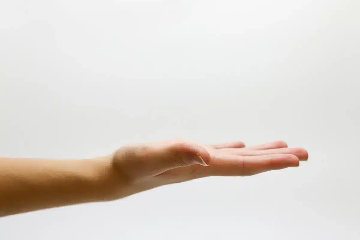 Hands holding a printed job offer beside a phone showing an inbox on a home desk