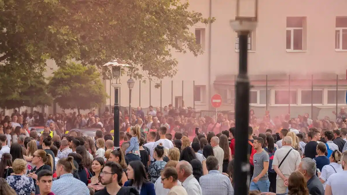Crowd gathered near a tree used as a vantage point at an outdoor concert