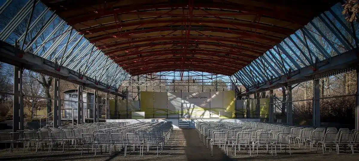 Hands holding an embroidered sash and folded cultural shawl on a table in a community hall