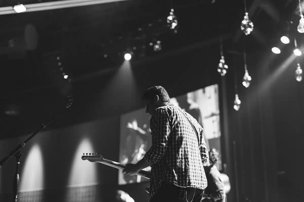 Empty stage with microphone stand and guitar case, suggesting an absent frontman