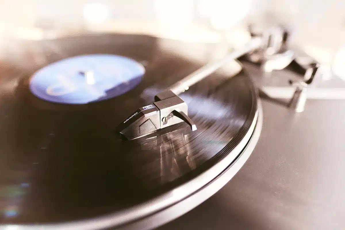 Vinyl records stacked beside a spinning turntable with warm stage lighting