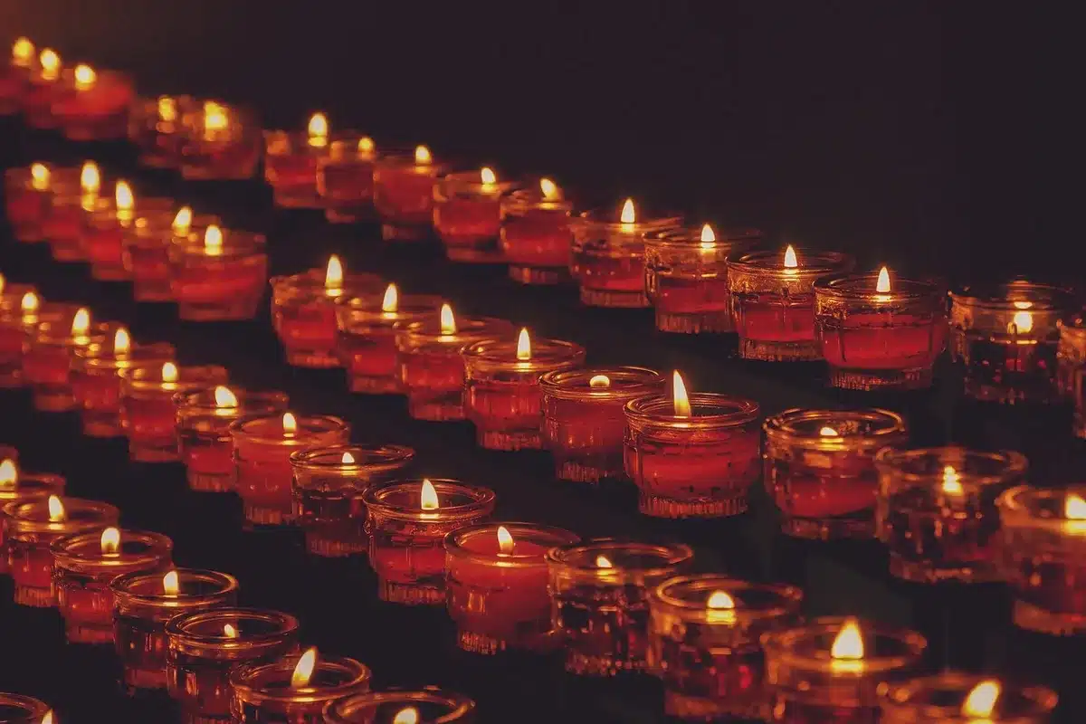 Dimly lit church interior with flickering candles and neon light reflecting off surfaces