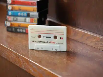 Drenched studio floor with tapes and a sampler, hands holding a wet cassette