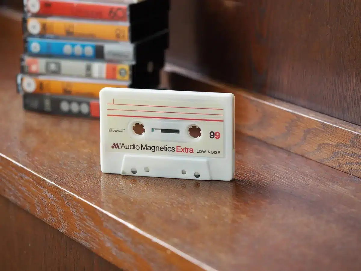 Drenched studio floor with tapes and a sampler, hands holding a wet cassette
