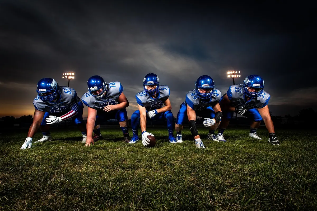 High school football players on field under Friday night stadium lights.
