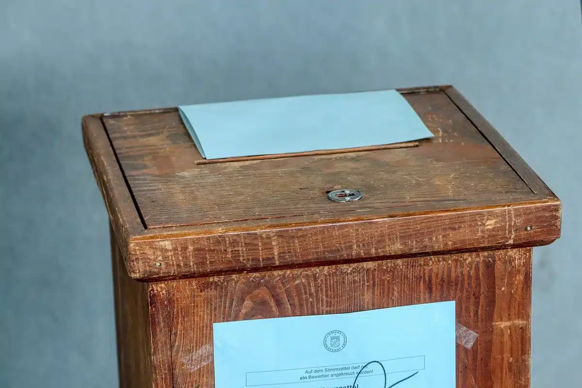 Close-up of a hand placing a ballot into a voting box