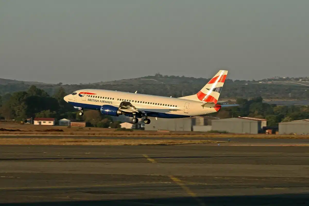 Silhouetted group near an aircraft doorway on a tarmac at dusk, staff movement suggesting urgency