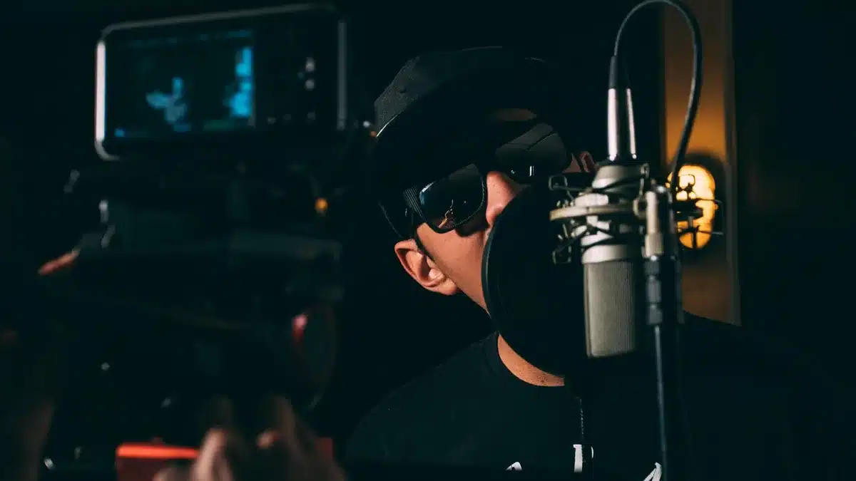 Silhouetted rapper performing intensely at a microphone in a dark recording studio