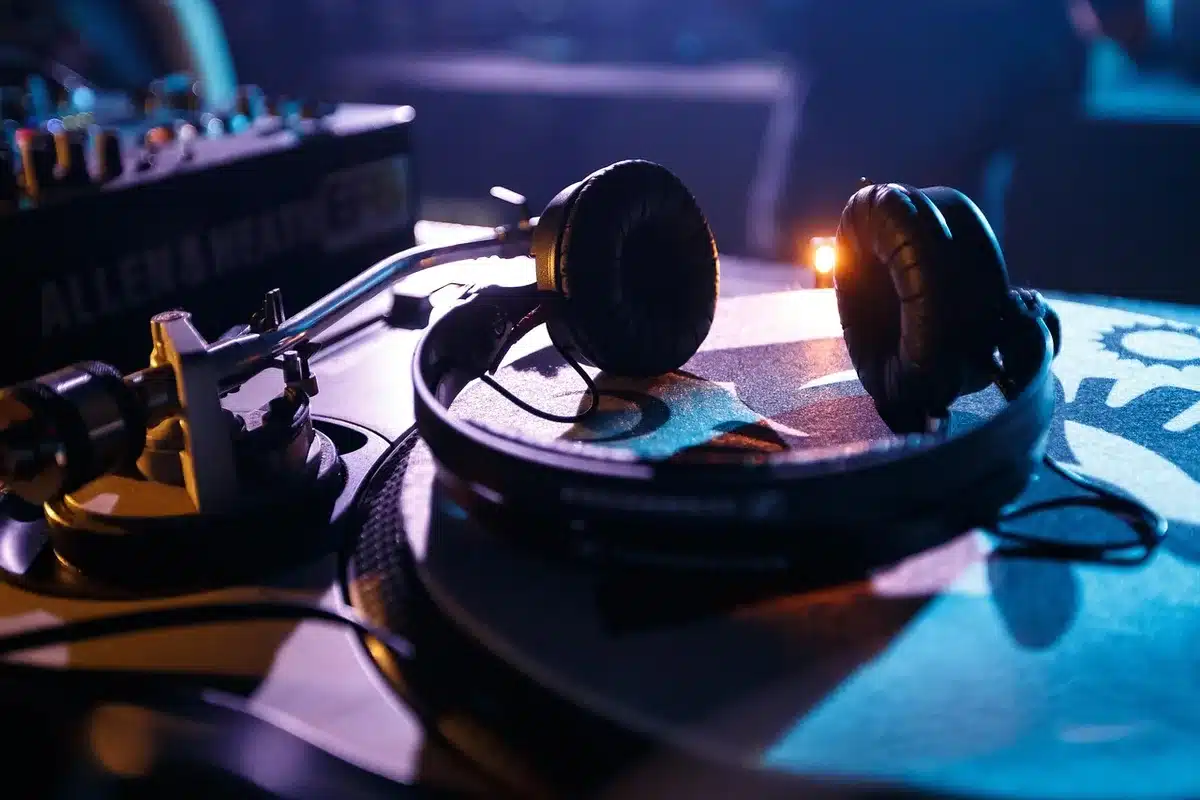 Person's hands digging through vinyl crates beside a turntable in a dim backroom