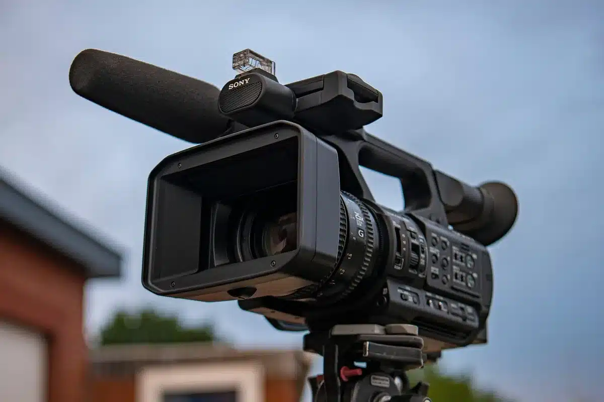 Parent watching a youth soccer match while a camera on a tripod records