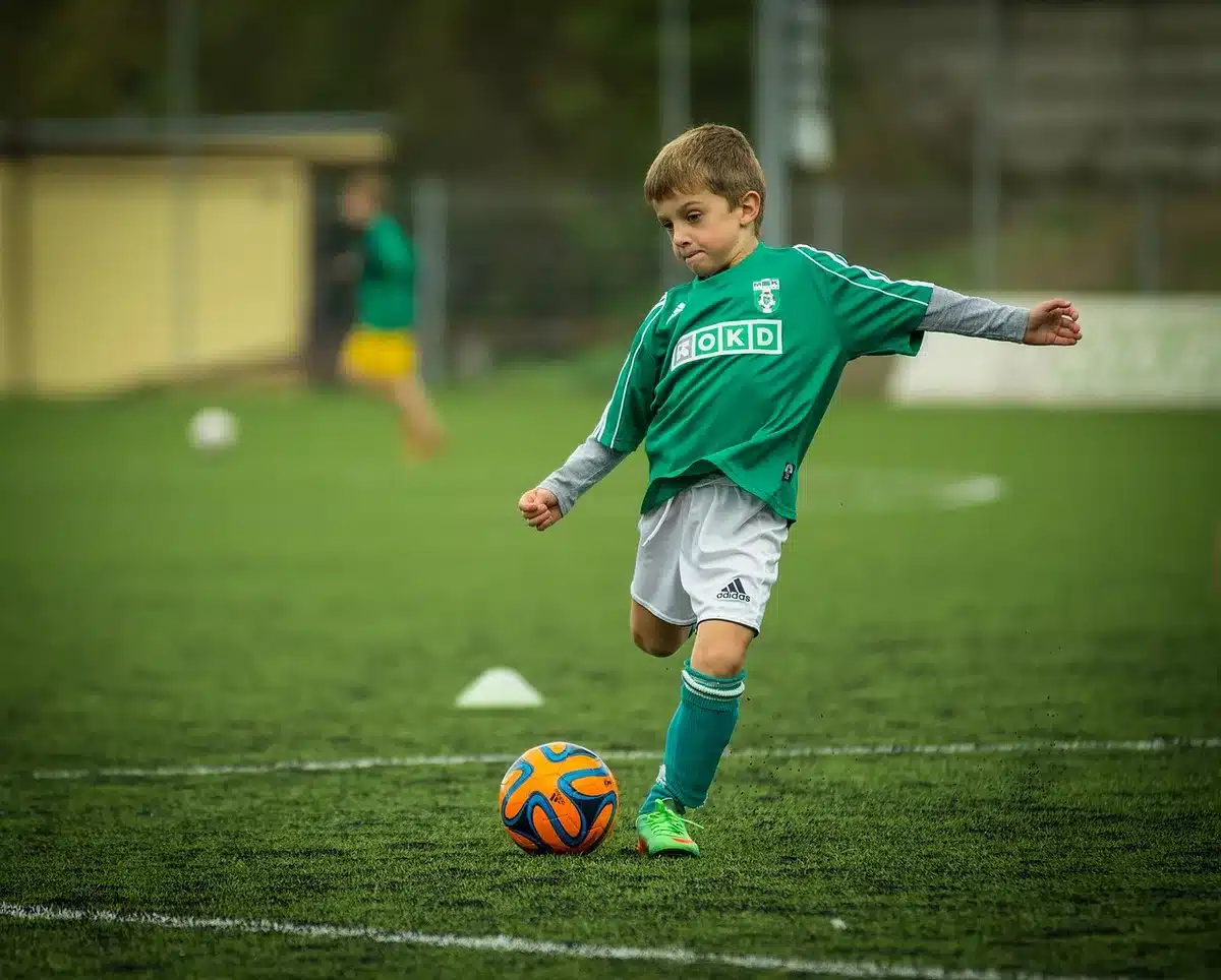 Young athlete sitting on bench holding knee, coach nearby