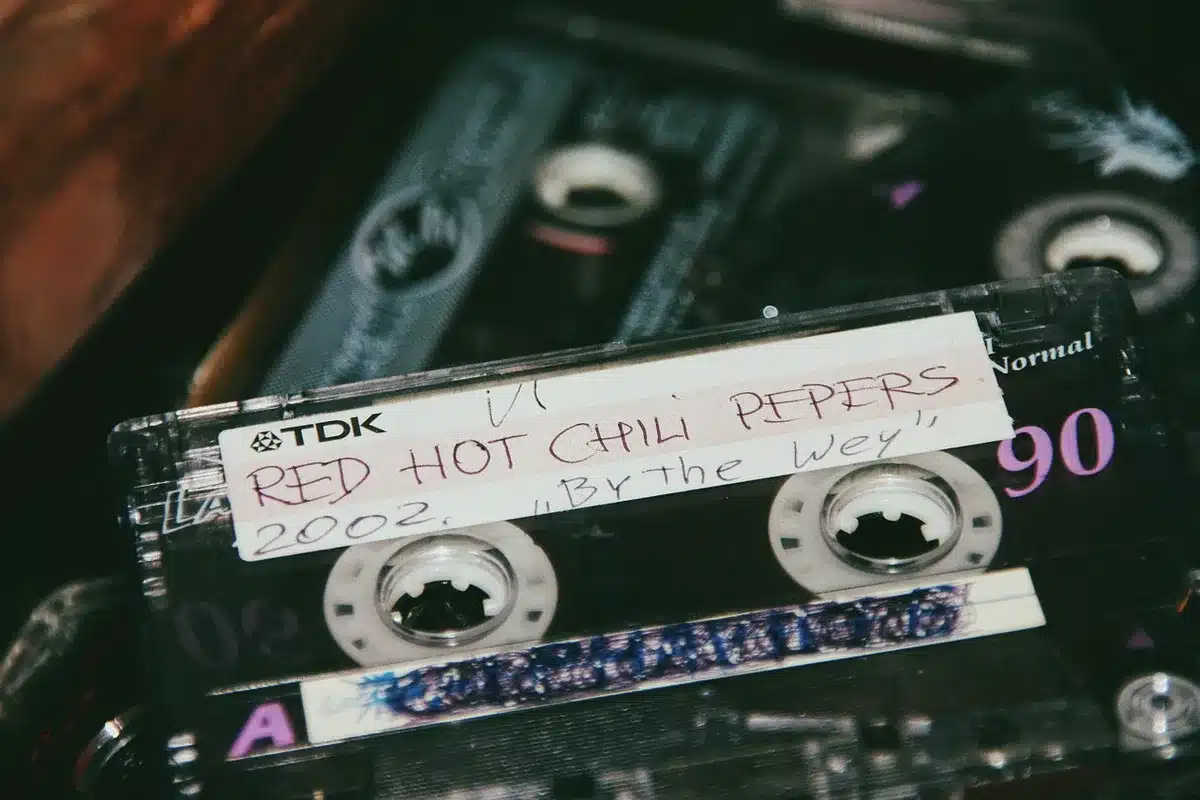 Hand holding a burned CD labeled mixtape beside a smartphone streaming music