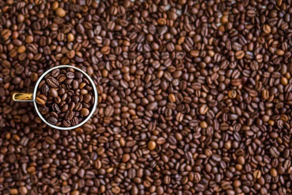 Steaming cup of coffee next to a laptop showing social feed
