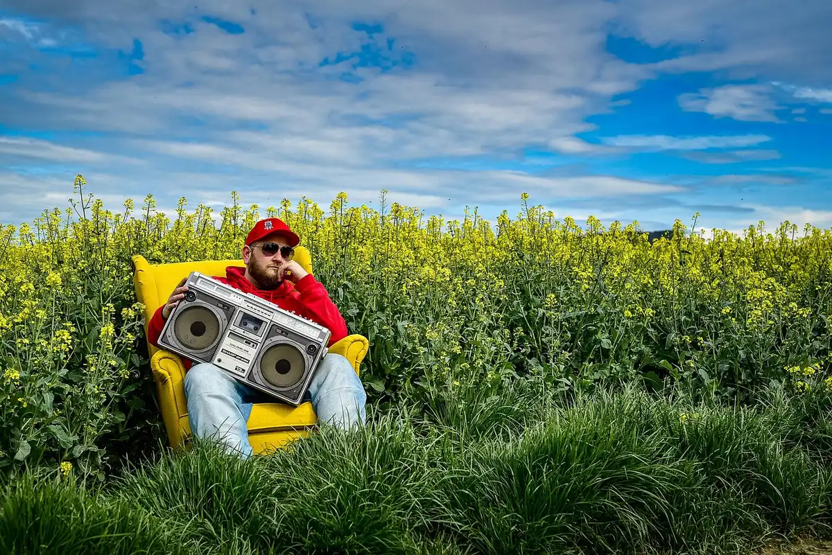 Group of anonymous friends singing around a boombox on a sunny backyard patio
