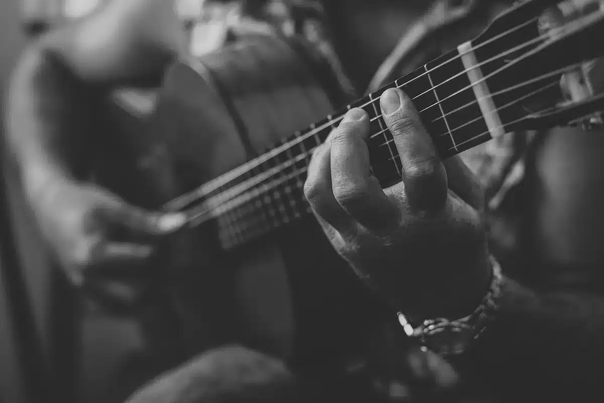 Hands playing an acoustic guitar outdoors during golden hour