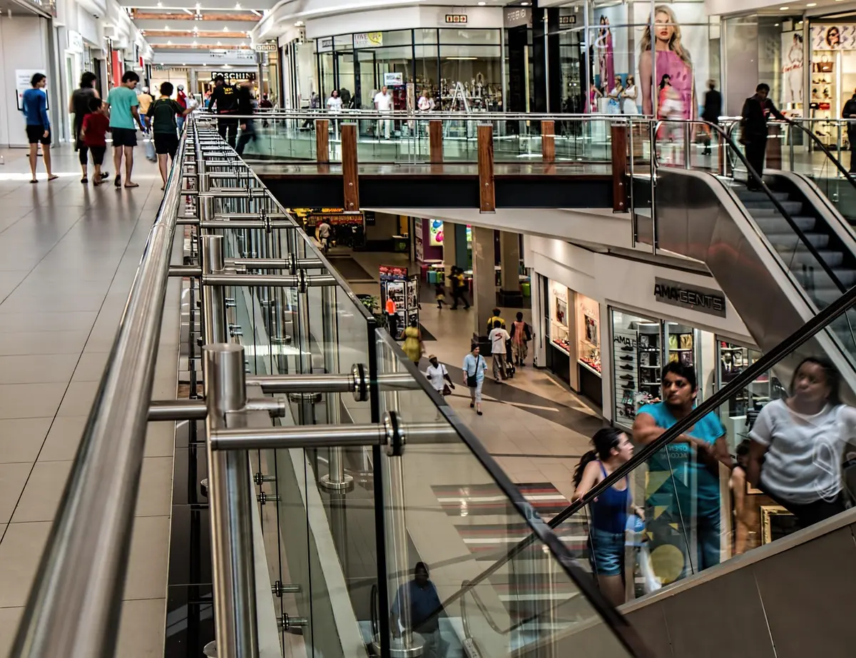 Silhouetted teens near an escalator in a shopping mall food court
