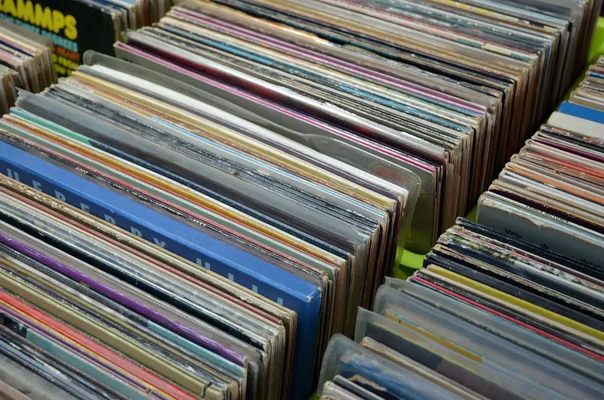 Hands browsing 90s vinyl in a vintage record shop with a turntable nearby