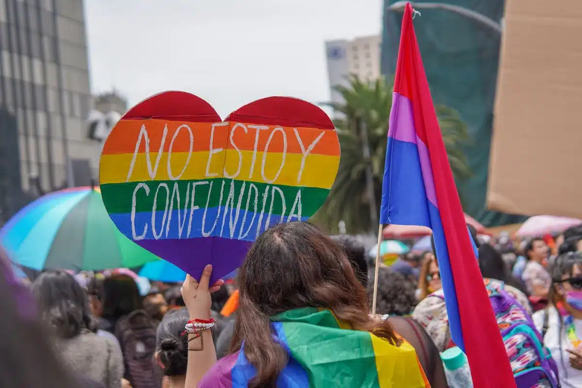 Crowd at an LGBTQ visibility protest holding signs and banners