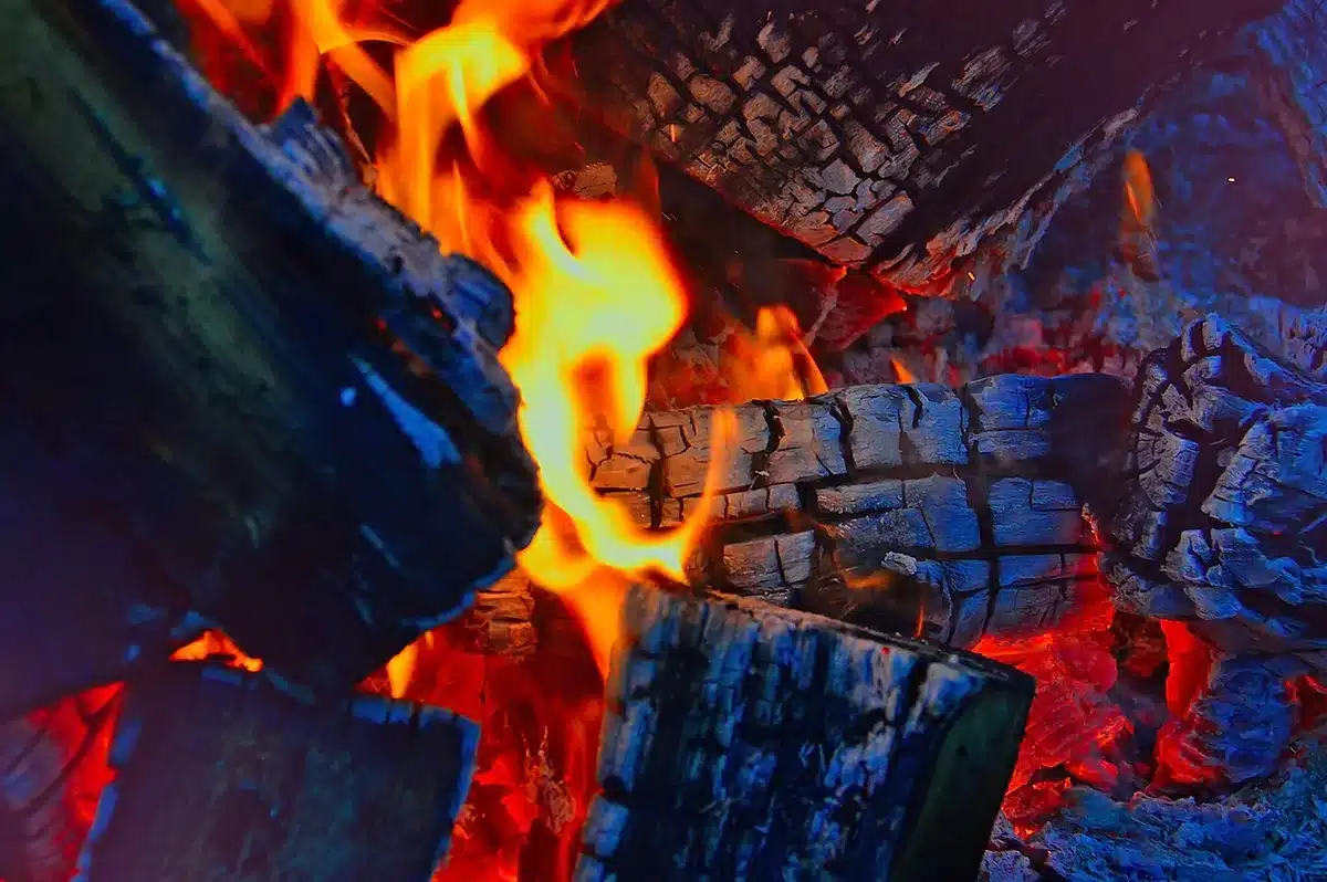 Portable speaker and batteries beside a campfire, ready for outdoor listening