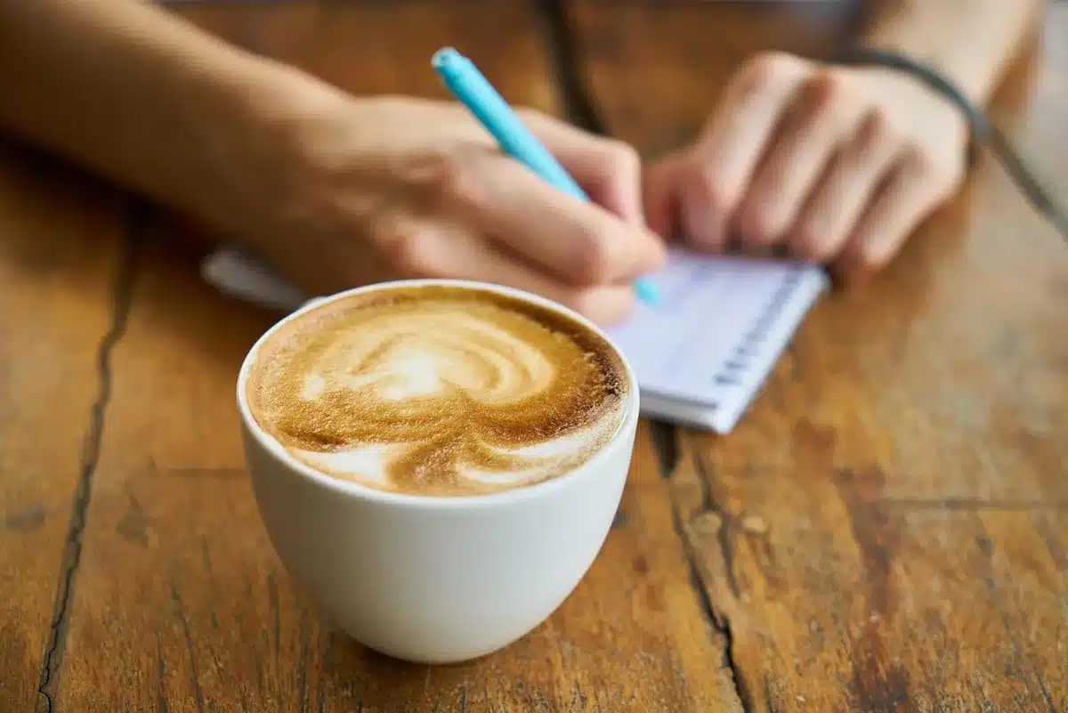 Over-ear headphones on a café table next to a laptop and coffee