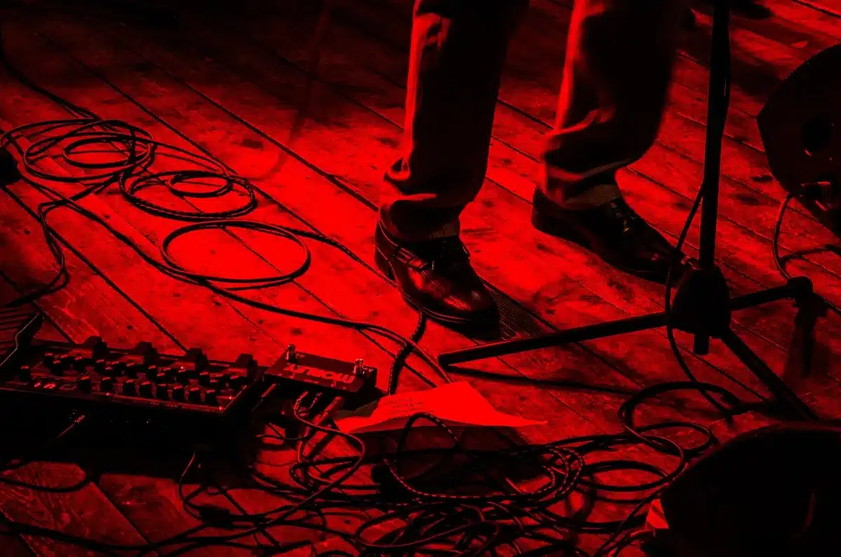 Silhouette of an electric guitar on stage beside a telescope and scattered notes
