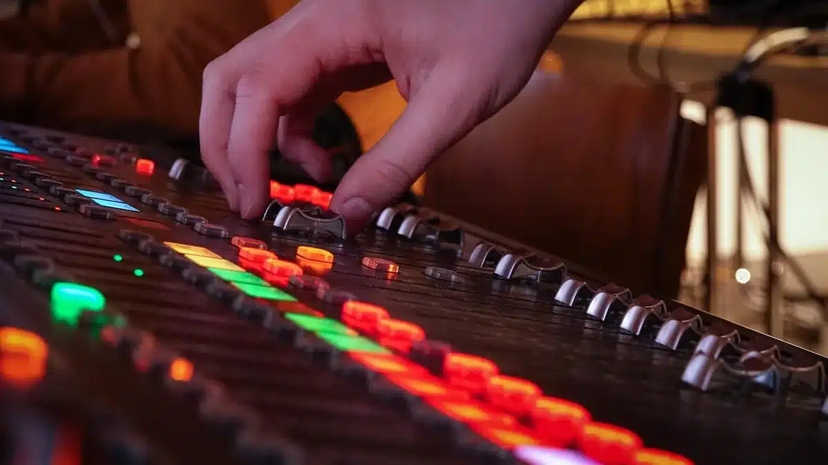 Studio corner with guitar, mixer and laptop showing a song waveform