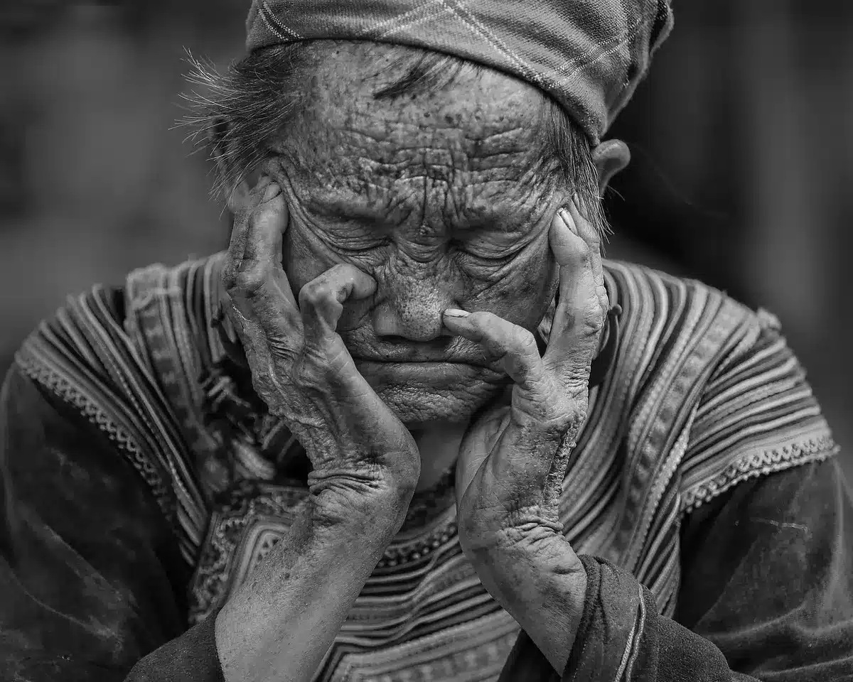 Older woman looking pensively away, hands folded