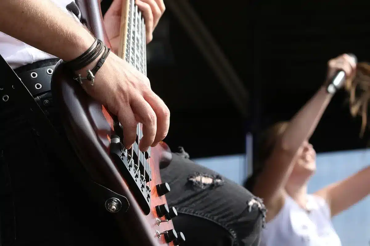 Guitarist playing heavy riff under stage lights as crowd reacts