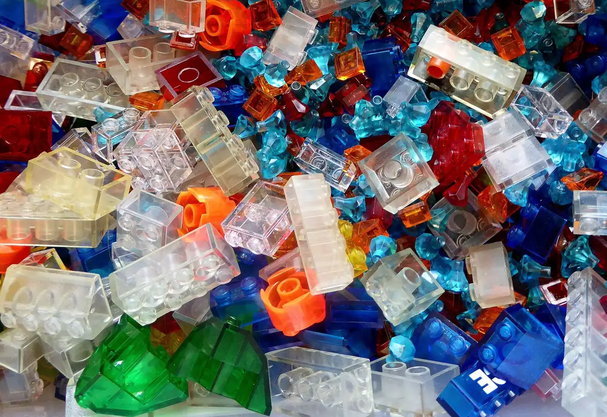 Hands assembling a Lego display with a laptop showing prices and a printout
