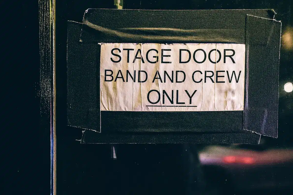 Backstage rehearsal area with instruments and anonymous masks hung on a wall
