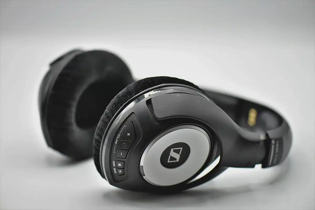 Headphones on a desk with audio waveforms on a laptop screen