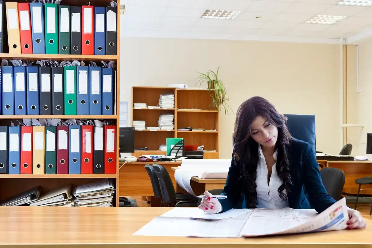 Stacks of documents and a computer screen showing data processing in an office