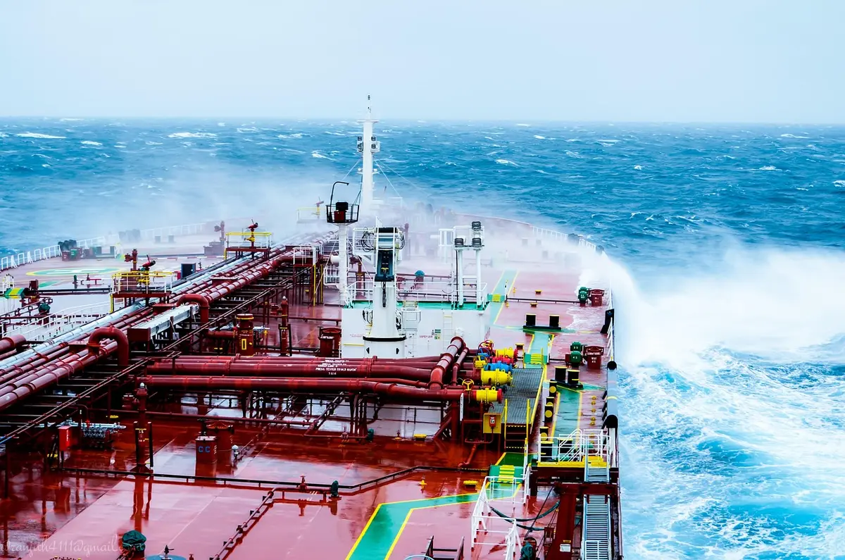 Cargo and oil tankers navigating a narrow strait under cloudy sky