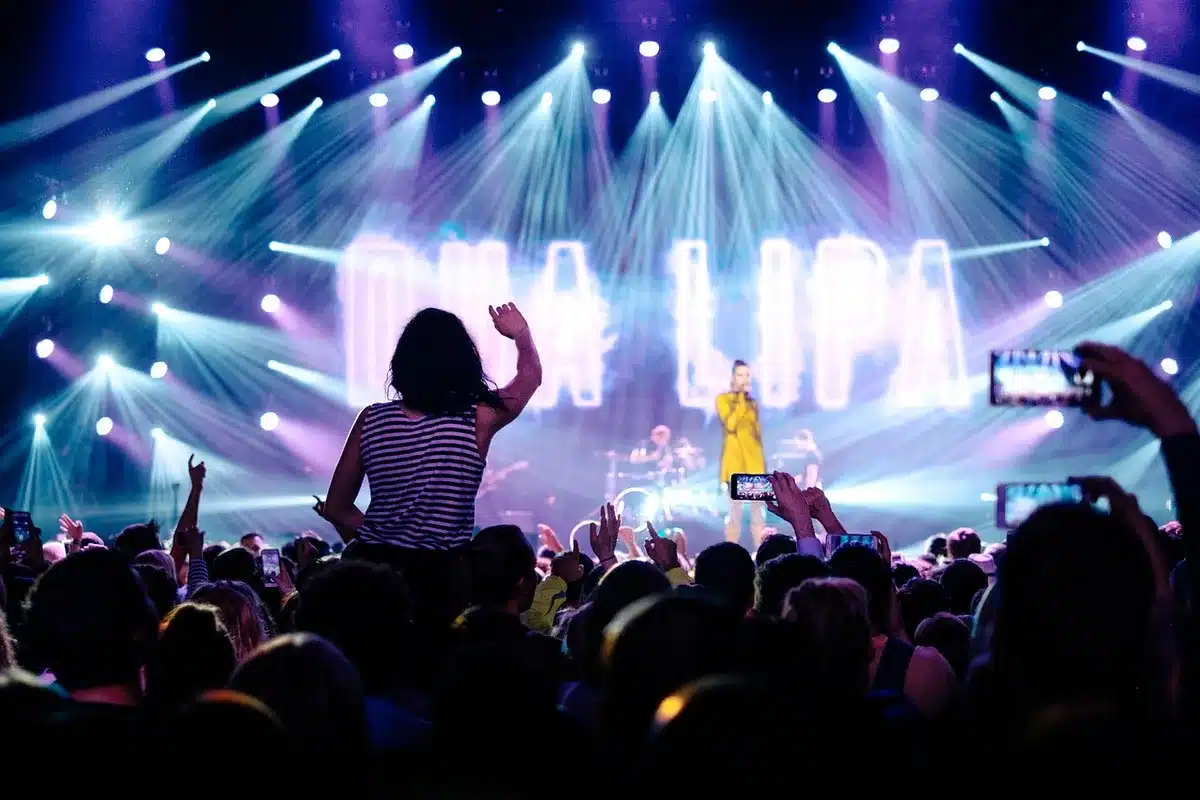 Silhouettes before an empty stage with microphones and a turned-away spotlight
